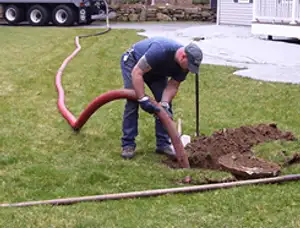 Septic pumping technician servicing a residential septic tank with a vacuum hose in Jacksonville, FL