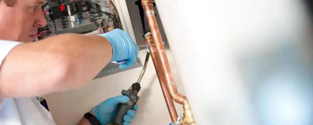 Water heater repair technician testing copper pipe connections and controls in Jacksonville, FL